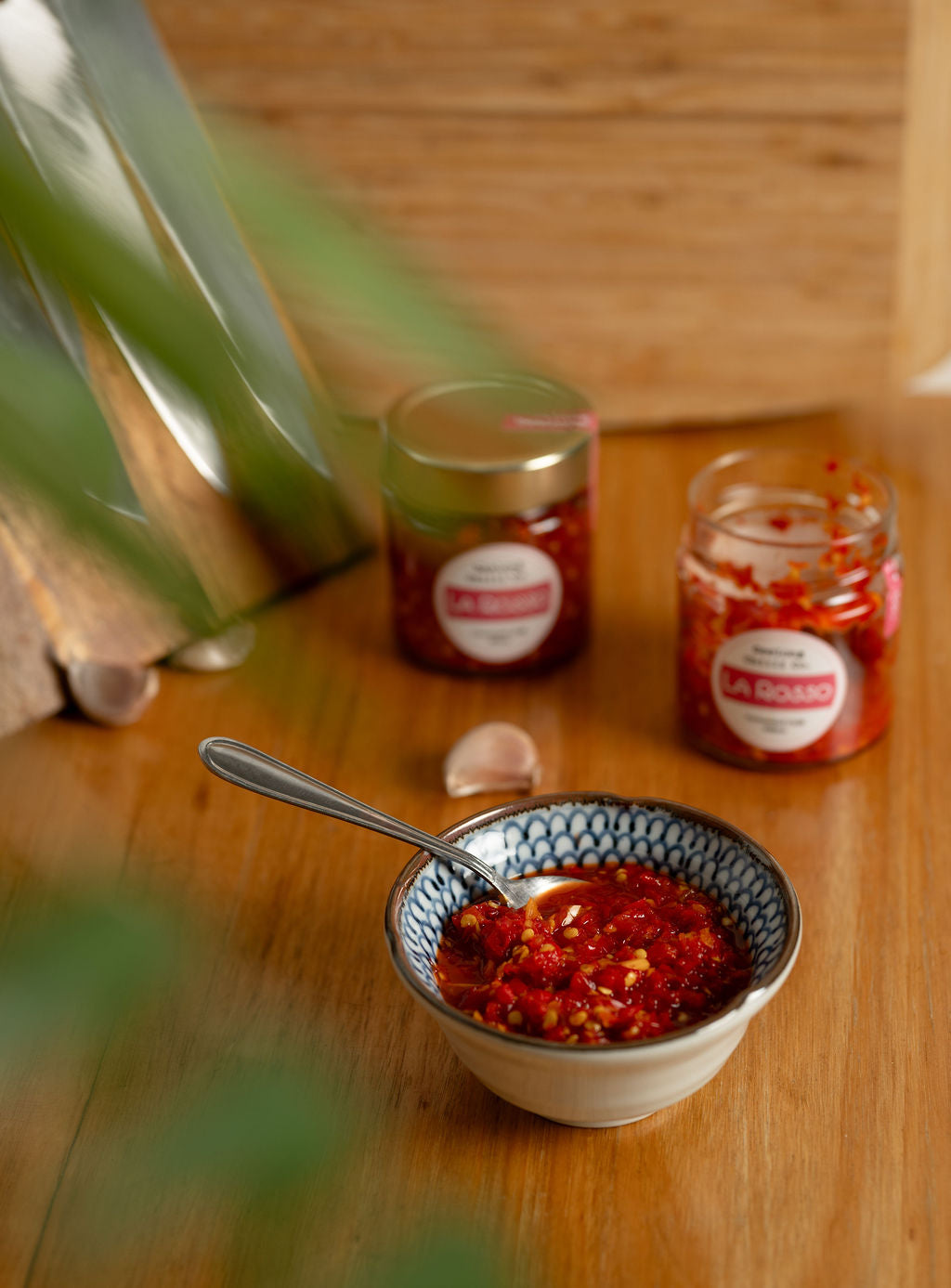 Bowl of red La Rosso chilli with a spoon on a wooden table.