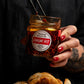 Person holding a jar of 'Umami Hit' with dumplings on a plate